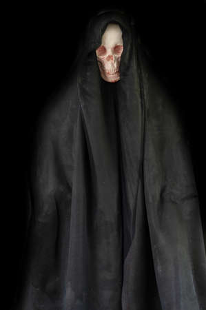 Human skull in black hood in darkness on grunge halloween background.の写真素材