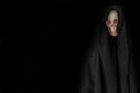Human skull in black hood in darkness on grunge halloween background.の写真素材