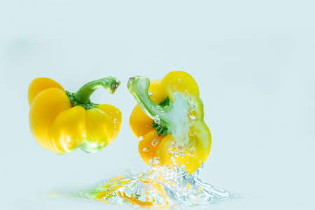 Yellow bell pepper, cut into pieces, splashes into the water. food ingredient concept