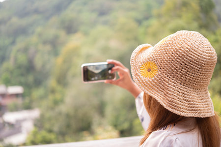 girl not seeing face in hat playing mobile phone on natural backgroundの写真素材
