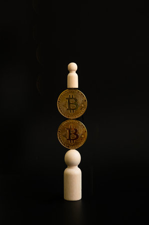 Bitcoin coin laying on person on wooden block on black background on balance conceptの写真素材