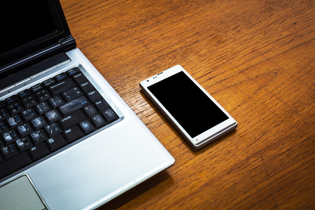 close up of the mobile phone near the laptopの写真素材