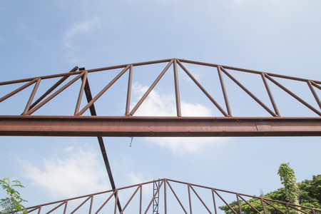 Steel roof trusses sitting on concrete pole view from inside home factory. Blue sky with clouds in background.の写真素材