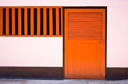 orange door closed on pink wall の写真素材