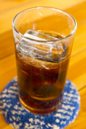 glass of cola with ice on wood background の写真素材
