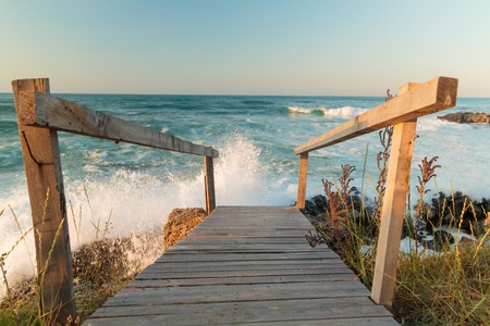 WOODEN BRIDGE NEAR THE BEACH ON SUNSET WITH BIG WAVES