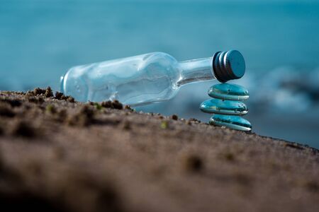 Transparent bottle on stack of glass stones symbolizing calmness