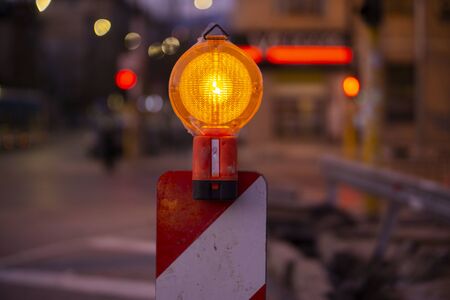 Road construction sign light in orange on a red and white standの写真素材