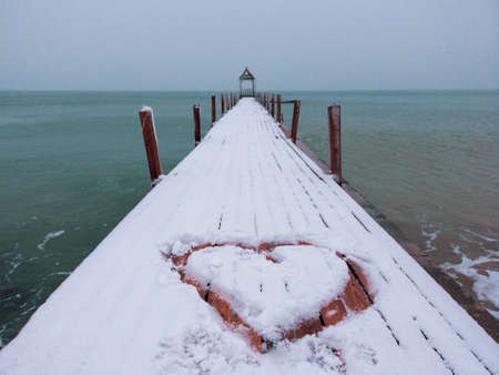 Heart shape on snow sea port with snowflakes fallingの写真素材
