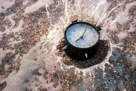 Alarm clock splashing in the beach waterの写真素材