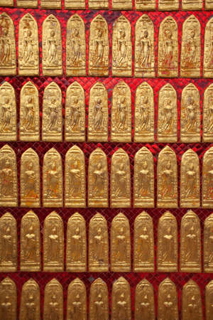 Little golden buddha on the wall background in Thailandの写真素材