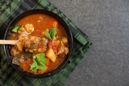 Meat stew with vegetables and herbs on old wooden tableの写真素材