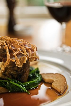 Crispy duck on a bed of spinach served with red wine in a restaurant.の写真素材