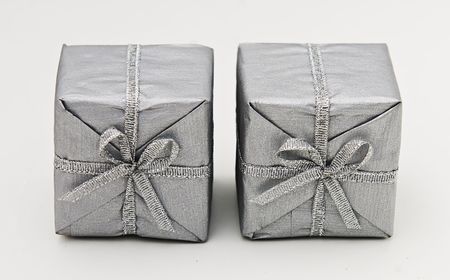 Pair of presents side by side wrapped in silver paper with silver bows.の写真素材