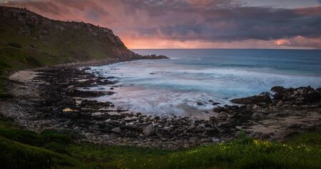 Sunset at a beautiful pristine rocky cove with water blurredの写真素材