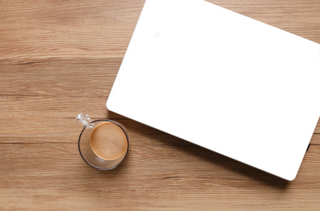 Top view of white laptop and a cup of coffee on wooden table.の写真素材