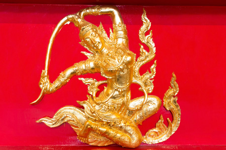 Golden female angel on red wooden background in Buddhist temple.の写真素材