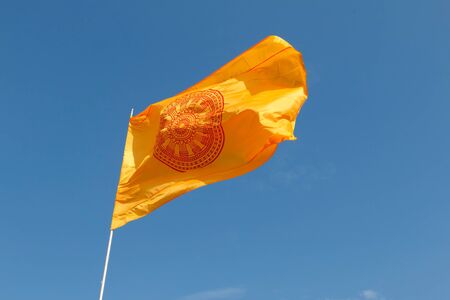 Yellow Buddhist flag of Thailand, Wheel of life flag waving on blue sky background.の写真素材