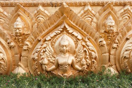 Golden carved cement background, statue. Traditional Thai style about Buddhist story,の写真素材