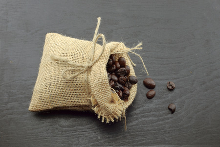 coffee beans in hemp sack bag isolated on wood background