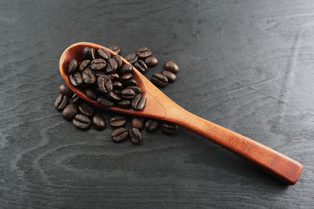 Coffee crop beans on spoon and wooden backgroundの写真素材