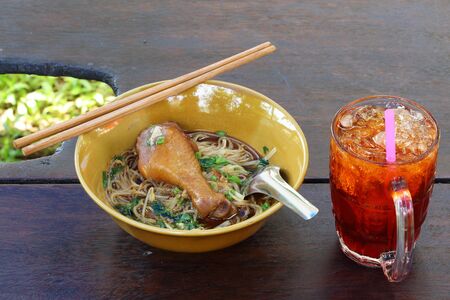 Chicken noodle with ice tea on the wooden tableの写真素材