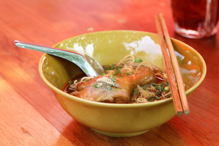 Chicken noodle with ice tea on the red wooden tableの写真素材