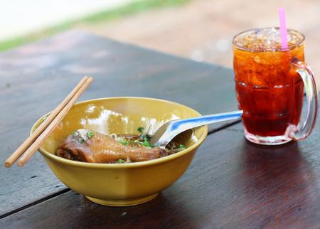 Chicken noodle with ice tea on the wooden tableの写真素材