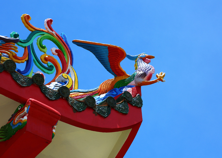 Phoenix statue on the roof of a Chinese temple under blue sky view from belowの写真素材