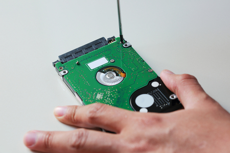 hand with screwdriver repairing hard driveの写真素材