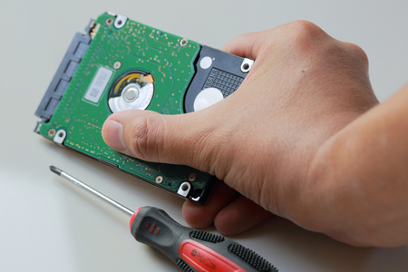 man's hand hold the hard drive with screwdriver