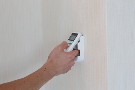 Hand with remote control directed on the air conditionerの写真素材