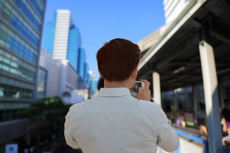 Man taking a photo of people walking on skywalk with smartphoneの写真素材
