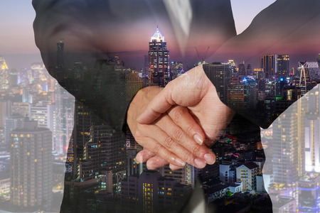 Double exposure of handshake and night city, business backgroundの写真素材