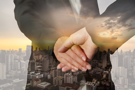 Double exposure of handshake and Cityscape sunsetの写真素材