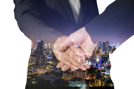 Double exposure of handshake and night city on white backgroundの写真素材