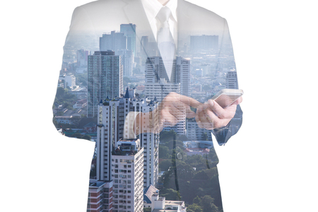 Double exposure of business man hand hold and touch screen smart phone, mobile and cityの写真素材