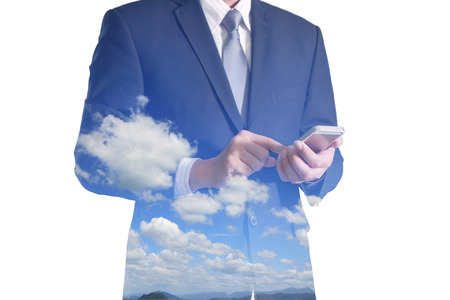 Double exposure of business man hand hold and touch screen smart phone, mobile, clouds and blue skyの写真素材