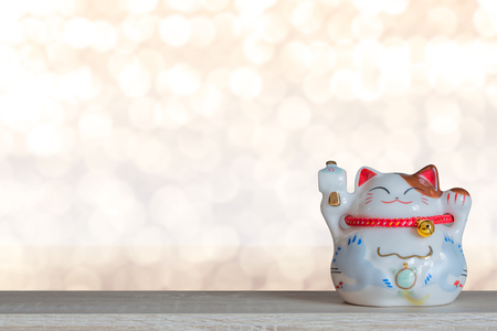 Beckoning lucky cat piggy bank with light bokeh background, abstract background to time to start to saving or lucky for keep money concept.の写真素材