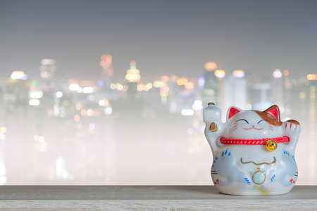Lucky cat piggy bank with bokeh city background, abstract background to time to start to saving or lucky for keep money concept.の写真素材