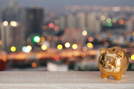Golden piggy bank with bokeh night urban background, abstract background to time to start to saving or solution for keep money.の写真素材