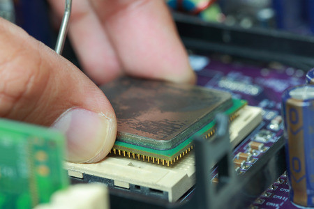 Selective focus of finger hold CPU microprocessor and plug in CPU microprocessor to motherboard socket, mainboard computer.の写真素材