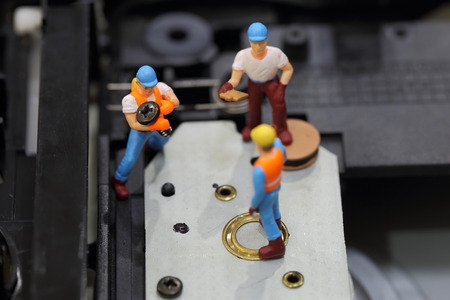 Selective focus of miniature engineer and worker fixed to hold screw for repair cd rom of computer...