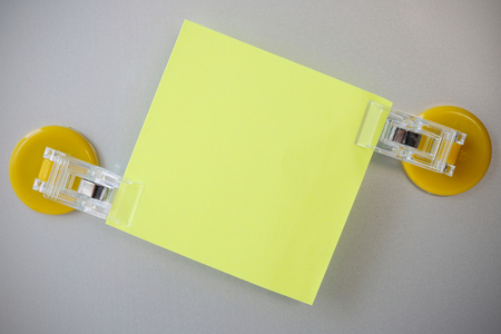Yellow notes clip by yellow clip magnet on gray refrigerator background.の写真素材