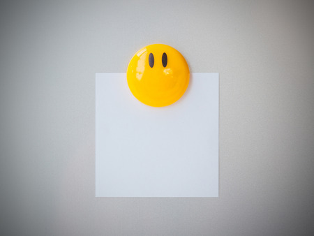 Yellow magnet paper clip on gray refrigerator background, abstract background.の写真素材