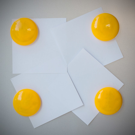 Yellow magnet paper clip on gray refrigerator background for input text.の写真素材