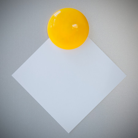 Yellow magnet paper clip on gray refrigerator background for note or write.の写真素材