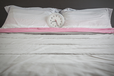 Clock on the bed as wake up in the morning concept.の写真素材