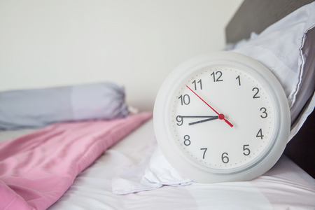Close up of the clock on the bed as start up morning concept.の写真素材