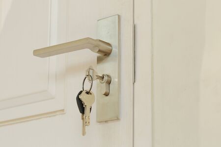 Key insert and hold in metallic knob on white door horizontalの写真素材